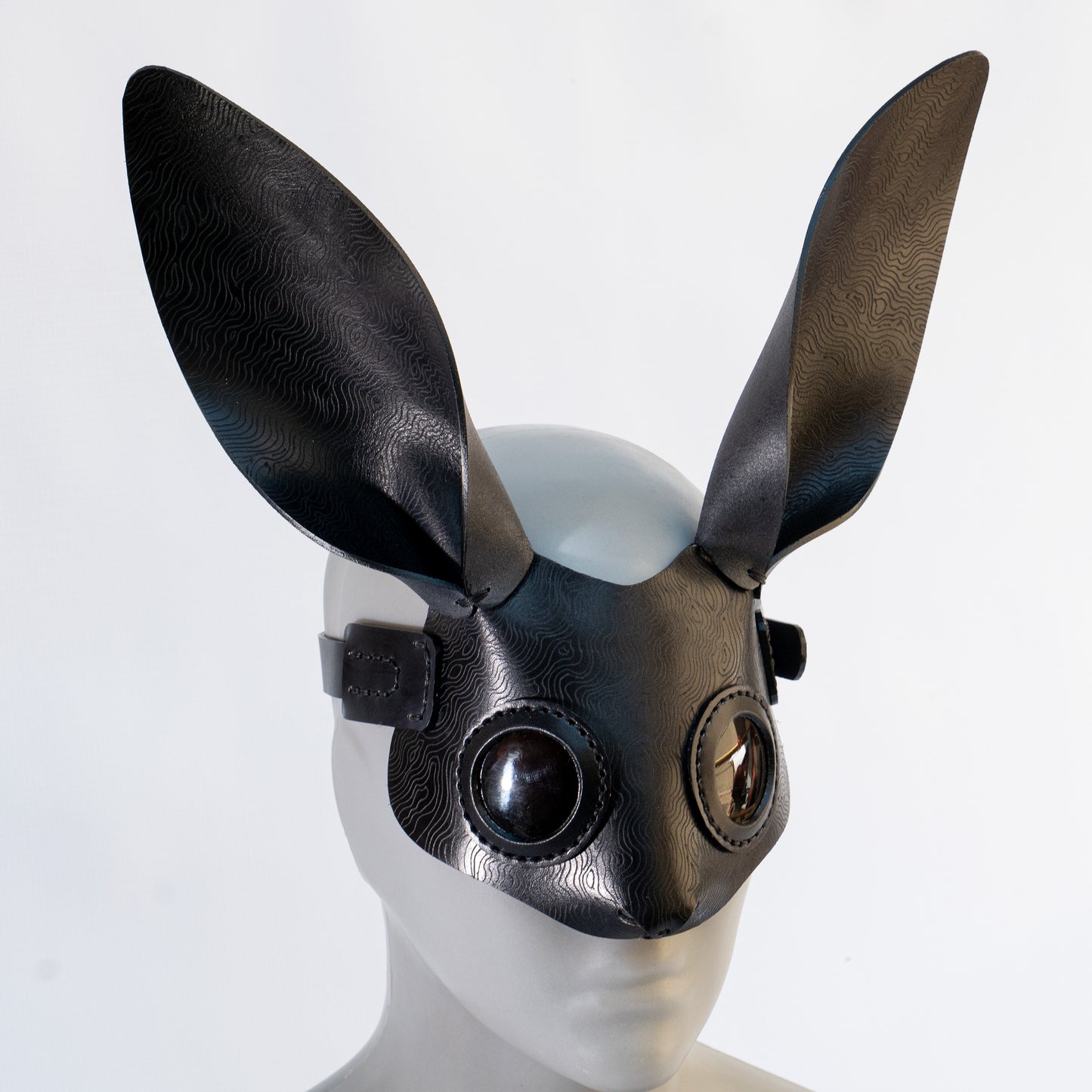 Bunny leather mask made by Atom Leather, from vegetable tanned leather, hot etched, on a mannequin head against a white background.