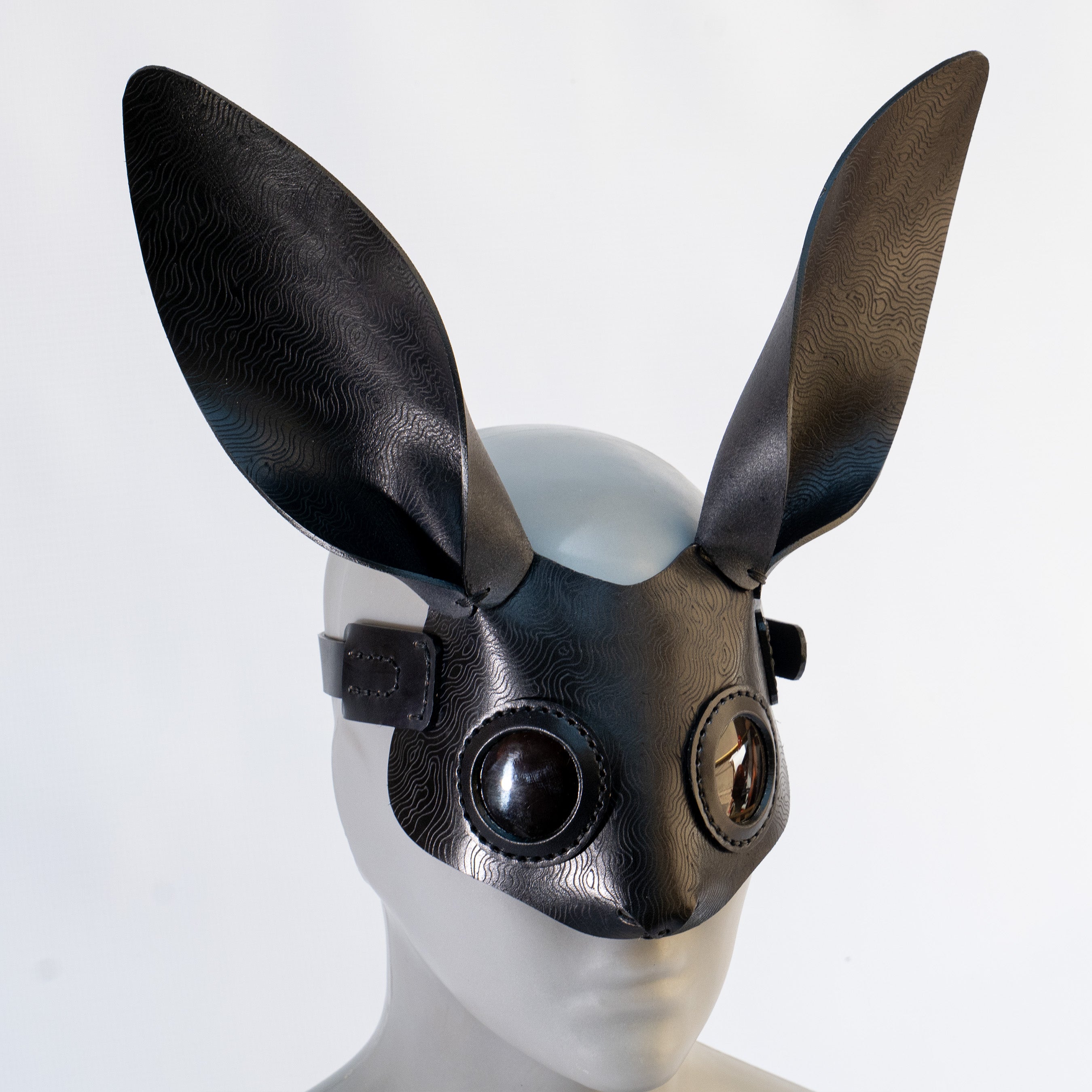 Bunny leather mask made by Atom Leather, from vegetable tanned leather, hot etched, on a mannequin head against a white background.