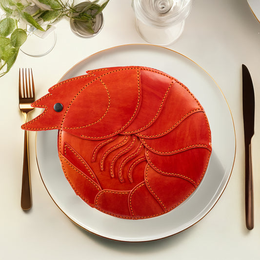 Photo of a limited-edition shrimp leather handbag with hand-dyed orange texture by ATOM LEATHER. The bag is placed in an elegant dish, as it is real shrimp.